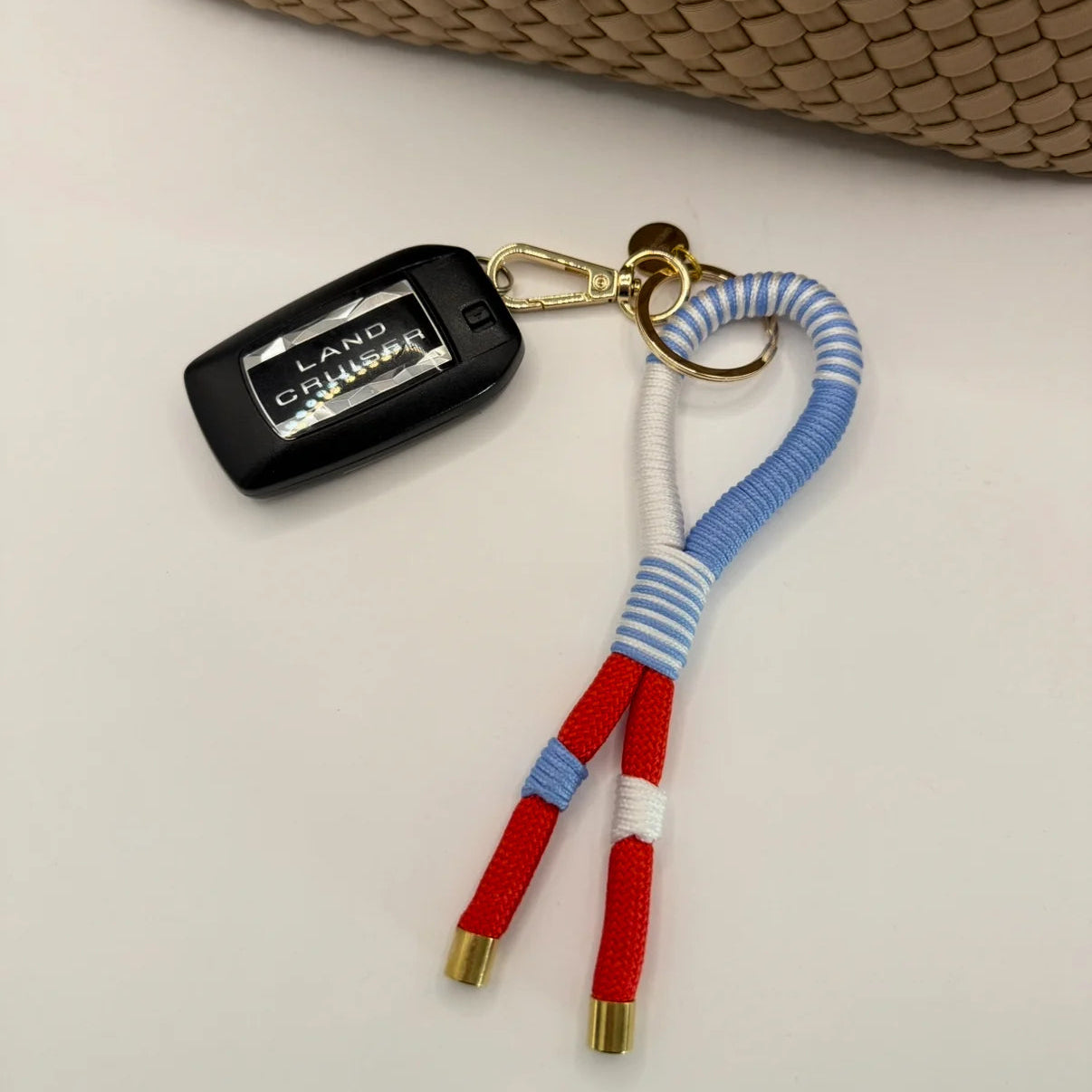 Keychain with red, white, and blue striped design attached to a car key fob on a light background.